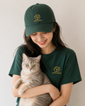 Person wearing a green 'Lucky Mustard' cap and t-shirt, holding a cat.